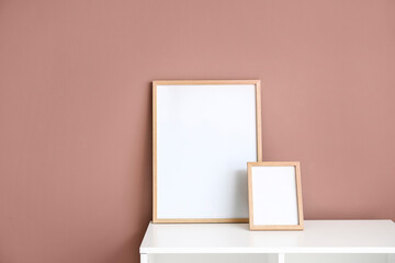 Blank frames on white shelf near color wall