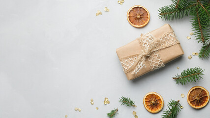 Fototapeta na wymiar Christmas present wrapped in kraft paper on grey canvas backdrop with copy space. Christmas and New Year banner. Gift box and Christmas decoration top view.