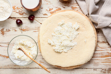 Fresh dough and ingredients for preparing tasty khachapuri on light wooden background