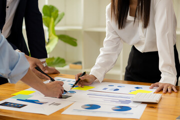 Two businessmen with pens pointing to a graph discussing data with modern laptops on a desk....