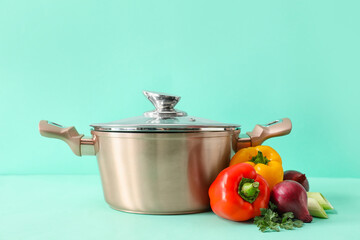 Cooking pot with vegetables for vegan soup on color background