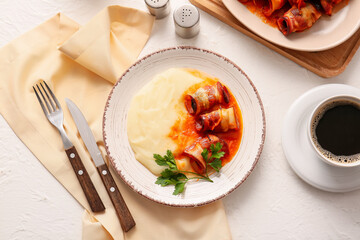 Plate with mashed potatoes, prunes baked in crispy bacon, gravy sauce and parsley on light table