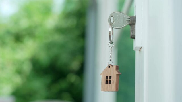 Landlord for new home. The house key for unlocking a new house is plugged into the door.The keychain is blowing in the wind.