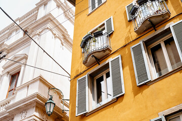 Fototapeta na wymiar Flowers on the balconies and shutters on the windows of the old house. Bergamo, Italy