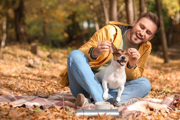 Handsome man with funny Jack Russel terrier in park on autumn day