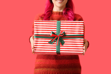 Beautiful woman with Christmas gift on red background, closeup