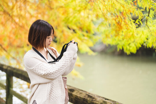 紅葉の公園でカメラを持って写真を撮る女性