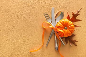 Composition with table setting, pumpkin and autumn leaves on beige background