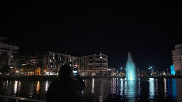 A Girl is taking pictures of fountains at night in Port Marianne, Montpelier - France
