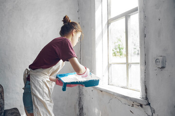woman painter paints window with brush renovation interior decoration