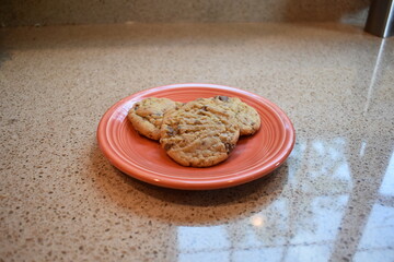 Close-up of three homemade chocolate chip cookies on an orange plate