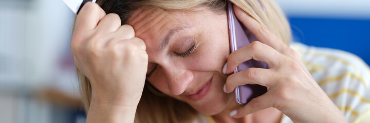 Upset woman talking on phone and holding plastic bank card