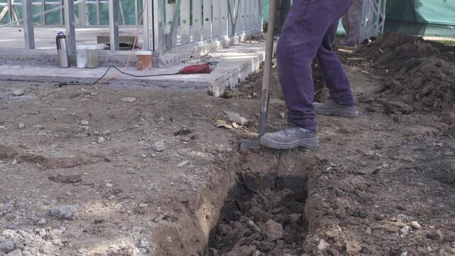 Close up shot of labor man digging hole with shovel on construction site - 4k track shot