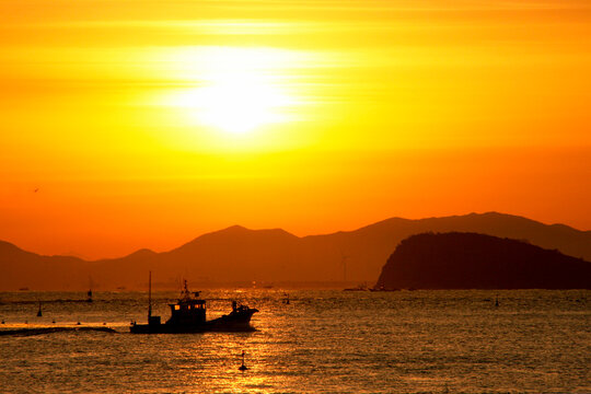 朝陽が昇って来た。港に入る漁船。遠近の山のシルエットが美しい。 © SYUUHOU