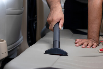 Car cleaning details - Man vacuuming in car cabin Professional car interior upholstery vacuum...