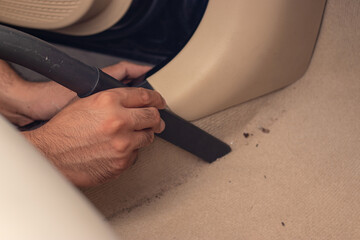 Car cleaning details - Man vacuuming floor in car cab Professional vacuum cleaner for car upholstery, carpet floor for dirty car interiors.