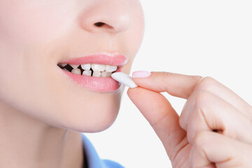 Womans face and female hand putting into mouth chewing gum