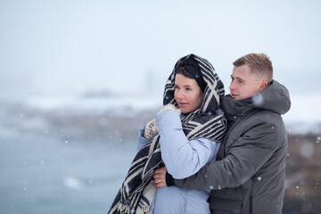 A couple in love walks on the shore of the winter sea, a man and a woman are frozen, it is snowing