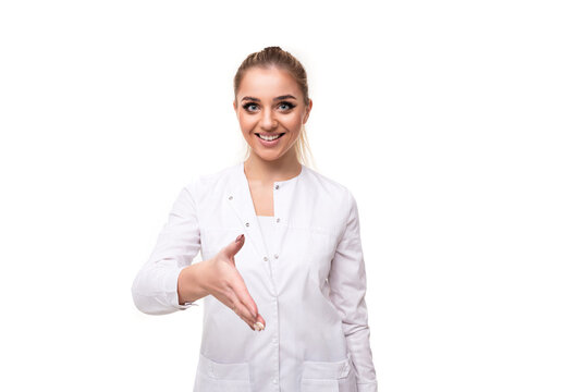 Photo of a beautiful pretty cute attractive positive smiling young blonde woman with a ponytail and makeup in a white medical coat of a nurse reaches out to say hello isolated on a white background