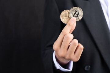 The man wearing a suit holding two bitcoins.