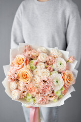 Flower arrangement in Wicker basket. Beautiful bouquet of mixed flowers in woman hand. Handsome fresh bouquet. Small flower shop and Flowers delivery.