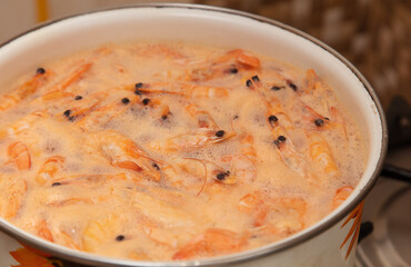 Red shrimps are boiled in a saucepan.