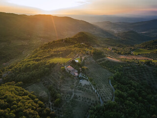 Aerial view of Tuscany Italy. Magic evening, sunset, Appenines mountains and farmland. Vineyards and olive trees plantations. Agriturismo. 