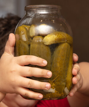 A jar of pickles in the hands of a boy.