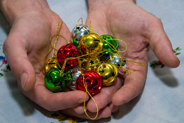 Multi-colored jingle bells in men's hands. Selective focus. On a light background. Close-up