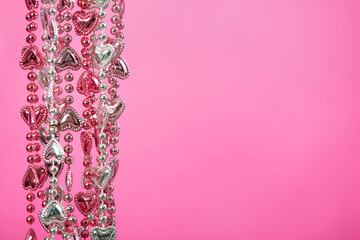 Pink and silver color, heart shaped beads against pink background with copy space. Valentine's Day and love concept.