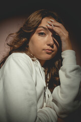 Young pretty woman in white sweater with curly hair opposite the lantern, on the pink background