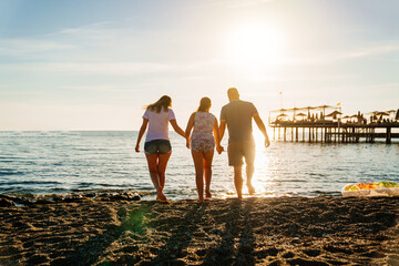 rear view. family in sunlight on shore of sea beach. family holidays at resort.