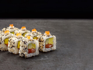 Salmon, avocado, egg omelette wrapped in rice. Served with red salmon caviar and sesame seeds. Japanese traditional sushi roll dish on concrete background. Single object. Copy space image
