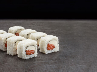 Inside out sushi roll with salmon, cream cheese inside. Japanese Dish on concrete background. Single object. Copy space image
