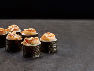 Japanese Maki sushi roll. Asian dish pieces with shrimp with peanut flakes on top served with sauce on dark concrete background. Copy space image. Single object. Inside out sushi

