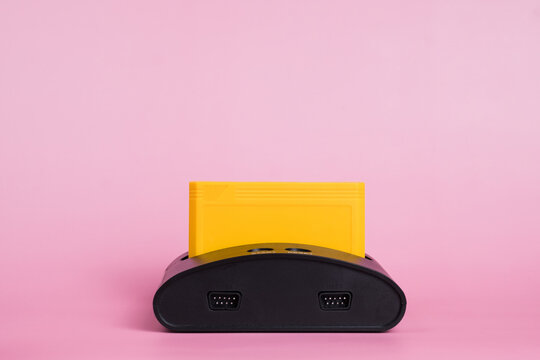 Old retro video game console with cartridge. Isolated on pink background. Copy space text.