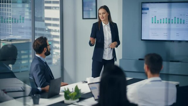 Diverse Office Conference Room Meeting: Motivated Female Digital Startup Owner Presents e-Commerce Fintech Growth Statistics to a Group of Investors. Wall TV with Big Data Analysis, Infographics