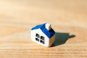 One miniature toy house on a wooden table.Yellow house model blurred background.Copy space.Closeup.