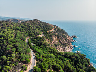 View from a drone on a mountain serpentine in the city of Tossa de Mar. Drone shot of a car driving...