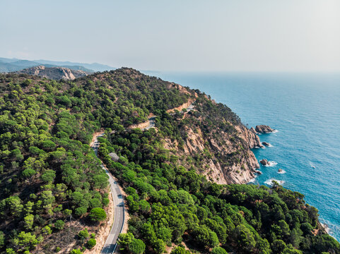 View from a drone on a mountain serpentine in the city of Tossa de Mar. Drone shot of a car driving along a mountain road. The resort town of Tossa de Mar near the Mediterranean Sea.