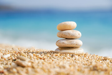 Fototapeta na wymiar Pyramid stones balance on the sand of the beach. Zen balance, minimalism, harmony and peace. Selective focus