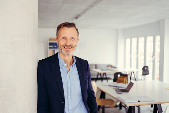 Senior businessman standing grinning at the camera