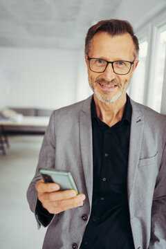 Smiling professional man standing holding his mobile phone