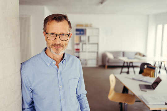 Relaxed thoughtful businessman in glasses scrutinising camera
