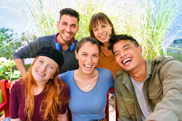 Obraz premium Positive young diverse friends smiling while taking selfie in garden
