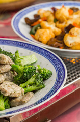 Two chinese dishes on a metal warming plate