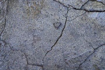 The concrete masonry has cracked as a result of bad weather conditions over many years. Wet cracked stone. 