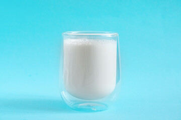 Milk in double glass insulate glass on blue minimal background. Lactose free milk made of vegan ingredients. Source of calcium