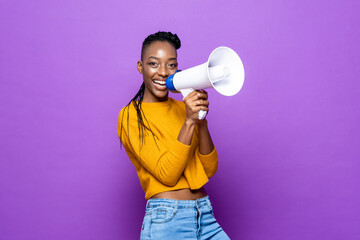 Young happy smiling African American woman holding megaphone in isolated purple color background