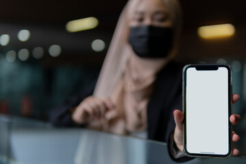 Young malay lady wearing face mask holding smartphone